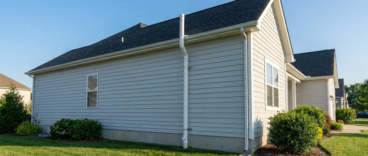 Sealed radon vent pipe running up the exterior wall of a home to above the roofline